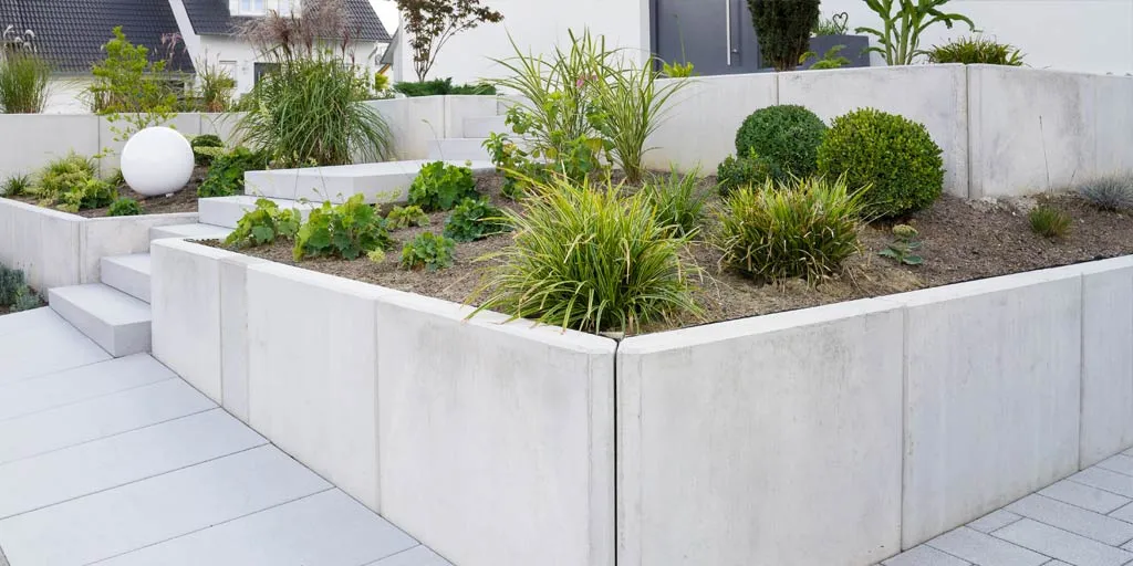 Modern concrete retaining walls with tiered landscaping and decorative plants