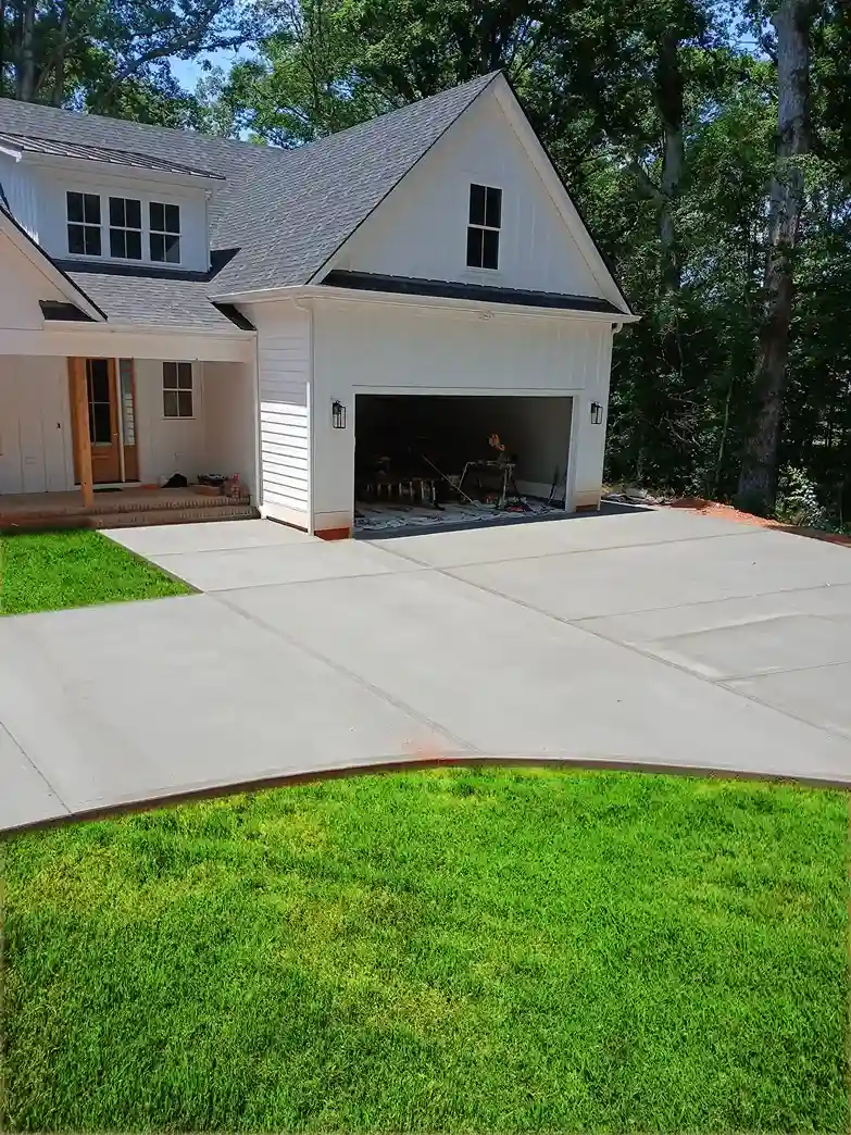 Freshly poured concrete driveway leading to a modern white home with a garage